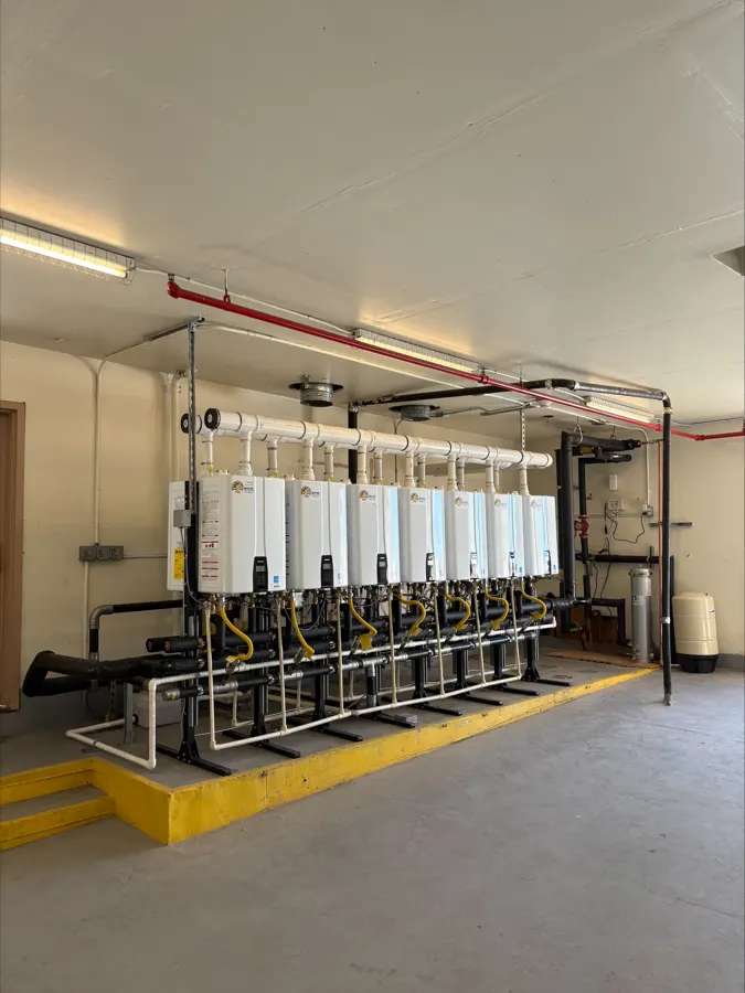 A rack of wall-mounted tankless water heaters installed by Water Heater Man